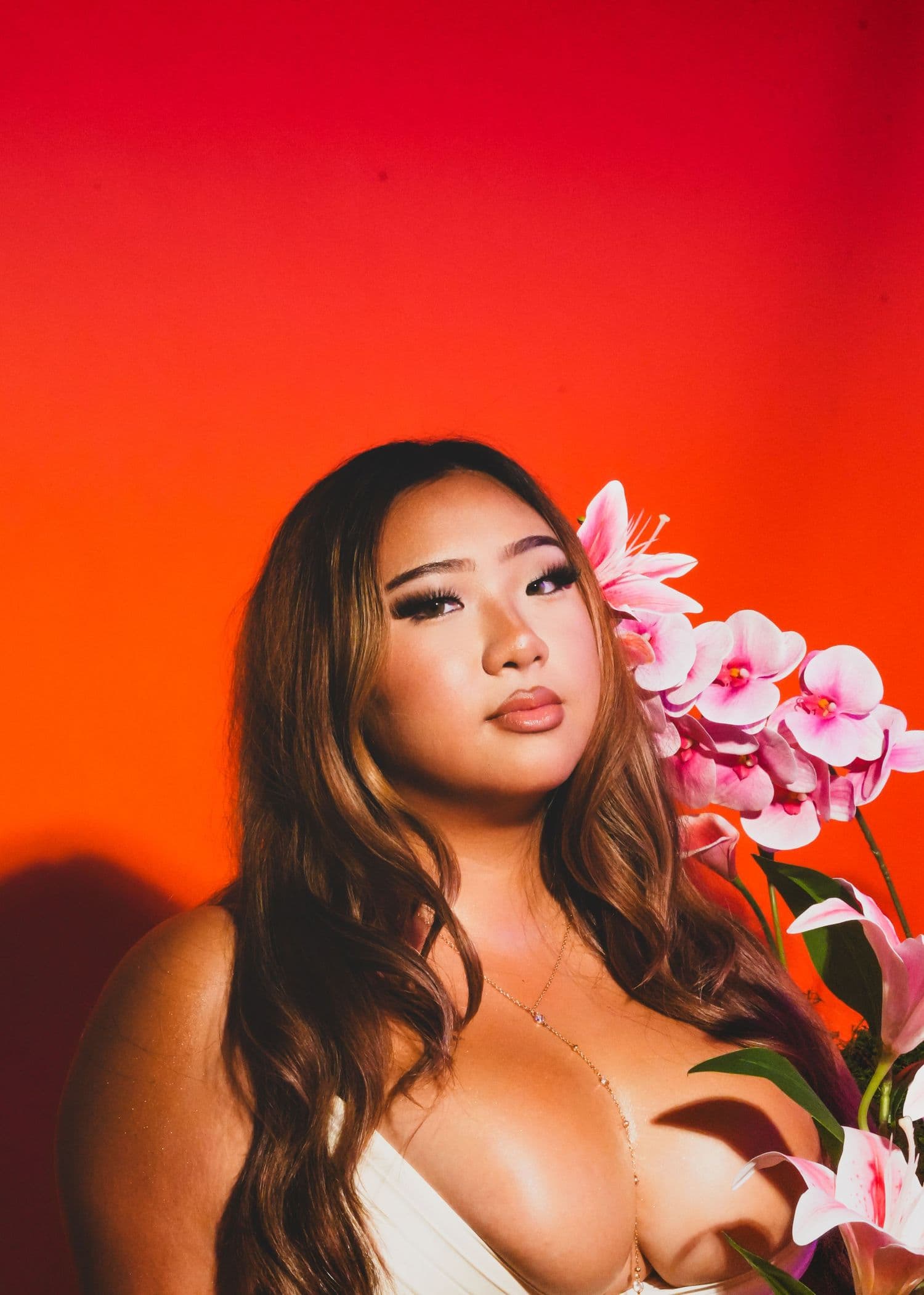 Portrait with long hair and pink flowers against a bright red backdrop