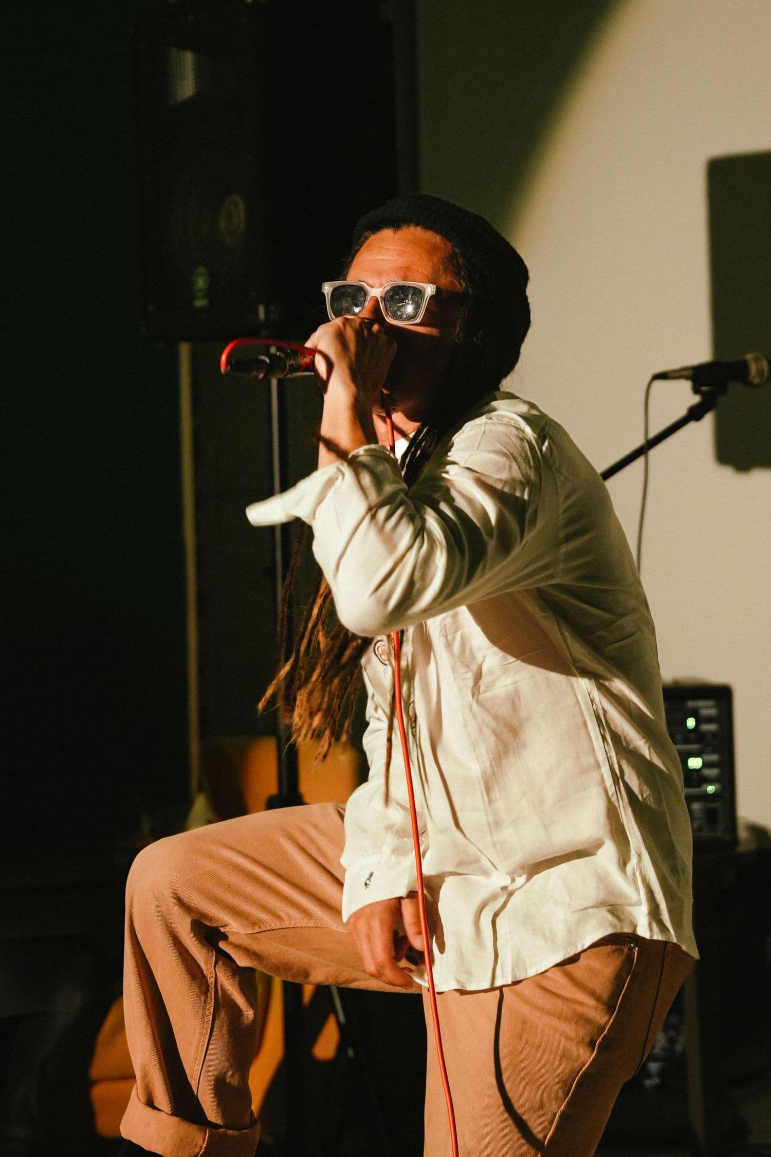 Performer in sunglasses singing into a microphone on stage